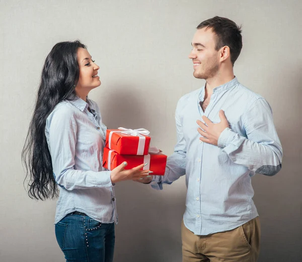 Chica Está Dando Regalo Novio Aislado Sobre Fondo Gris — Foto de Stock