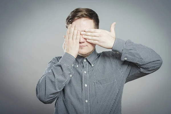 young man closes his eyes with his hands