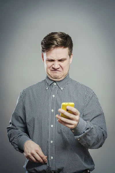 Förvirrad Ung Man Tittar Mobiltelefon — Stockfoto