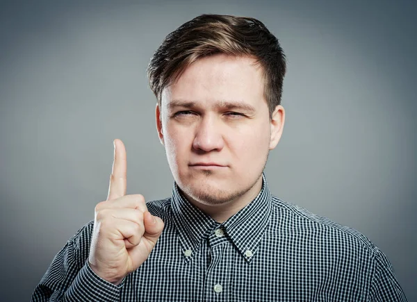 Gri arka planda duran gülümseyen genç adamın portresi. Dikey çekim.