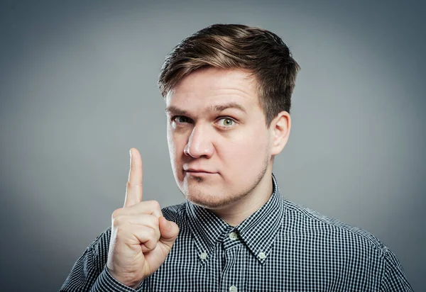 Gri arka planda duran gülümseyen genç adamın portresi. Dikey çekim.