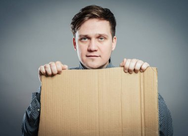 Sıradan bir genç adam yalnız bir kutu tutuyor.