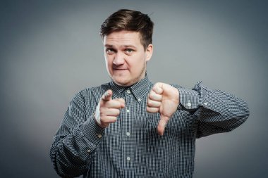 Gri arka planda baş parmak gösteren genç adam.