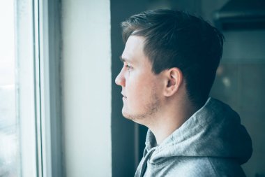 Elleri yanağında hayal kırıklığına uğramış genç bir adamın yakın plan portresi..