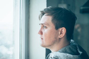 Elleri yanağında hayal kırıklığına uğramış genç bir adamın yakın plan portresi..