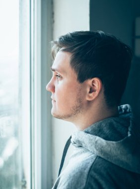 Elleri yanağında hayal kırıklığına uğramış genç bir adamın yakın plan portresi..