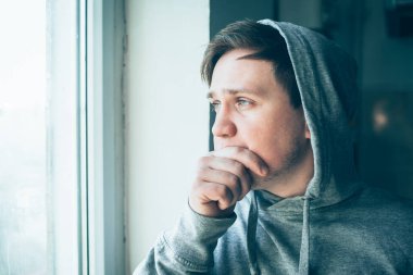 Elleri yanağında hayal kırıklığına uğramış genç bir adamın yakın plan portresi..