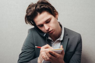 İşine odaklan. Kendine güveni tam bir genç adam telefonda konuşuyor ve bir şeyler yazıyor.