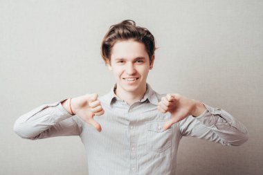 Yakın çekim portresi, genç yakışıklı adam baş parmak işareti gösteriyor, teklifi onaylamadığı için, durum. 