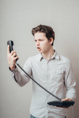 Eski bir telefonla konuşan genç bir adamın portresi. 