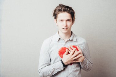 Elinde kırmızı bir kalp tutan genç bir adam.