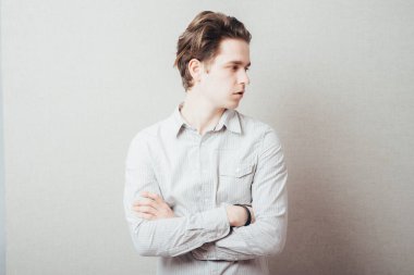 Gri arka planda elleri katlanmış ciddi bir adam.