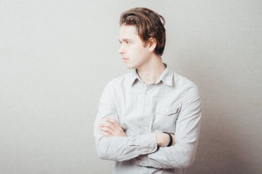 Gri arka planda elleri katlanmış ciddi bir adam.