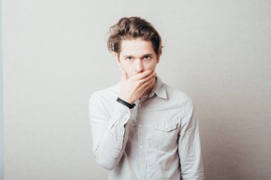 Genç adam elleriyle ağzını kapatıyor. 