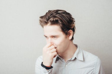 Yakından bakınca yakışıklı bir adamın portresi, burnunu kapatan bir iş adamı, bir şey kokuyor. Negatif insan yüz ifadeleri, duygular, duygular, tepki, tutum, davranış, algı