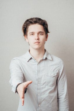 Mutlu gülümseyen genç iş adamı tokalaşmak için elini uzatıyor