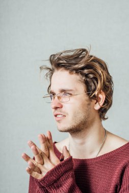 Gözlüklü adam birlikte dua ediyor. Gri bir arkaplanda.