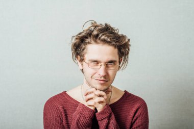 Gözlüklü adam dua ediyor. Gri bir arka planda elleri kavuşturulmuş..