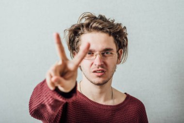 Bir erkek zaferin jestini gösterir. Gri bir arkaplanda.