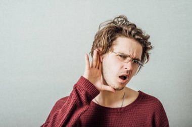 Eli kulağına yakın bir adam. Jest dinlemeden duyamaz, yüksek sesle konuşamaz. Gri bir arkaplanda