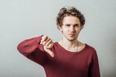 Gri arka planda baş parmak gösteren genç adam.