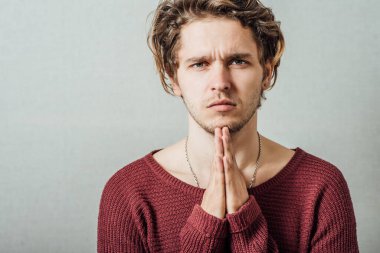 Bir erkek dua eder. Gri bir arkaplanda.