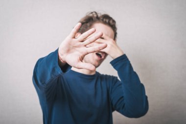 Genç adam yüzünü kapatarak gülüyor.