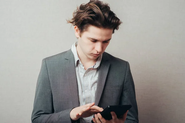 stock image Thinking young man with calculator on grey