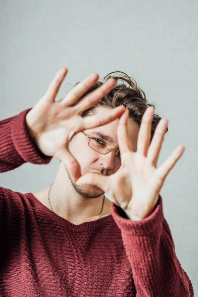 Hombre Mirando Través Sus Manos Forma Corazón Sobre Fondo Gris — Foto de Stock