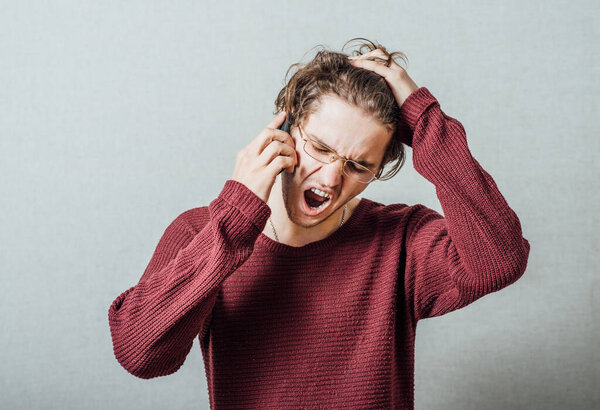 Man shouting on the phone. Gesture cry discontent, talking on the phone. On a gray background