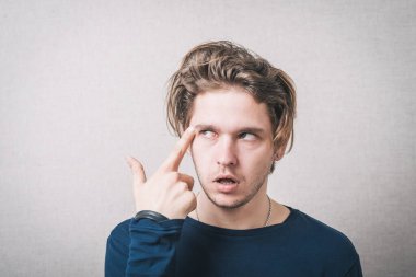 Adam parmağını şakağına dayıyor.