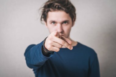 Bir adam işaret parmağını öne doğru gösterir. Gri arkaplan.