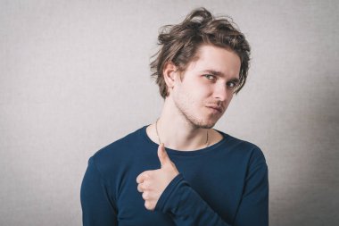 Başparmağını gösteren bir adam. Gri arkaplan.