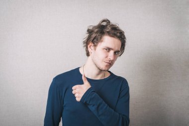 Başparmağını gösteren bir adam. Gri arkaplan.