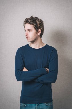 Adam kollarını göğsüne kadar kavuşturdu. Gri arkaplan.