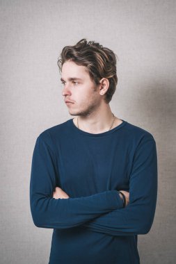 Adam kollarını göğsüne kadar kavuşturdu. Gri arkaplan.