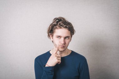 Yanağında parmak olan, diş ağrısı olan bir adam. Gri arkaplan.