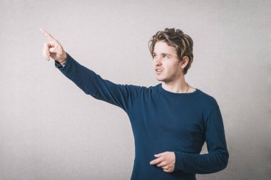 Bir adam işaret parmağını öne doğru gösterir, profil. Gri arkaplan.