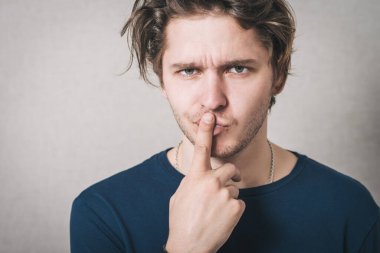 Adam parmaklarını ağzına sokmayı düşünüyor. Gri arkaplan
