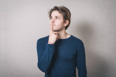 Adam parmaklarını ağzına sokmayı düşünüyor. Gri arkaplan