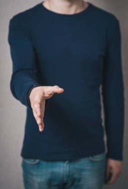 Adam merhaba demek için elini ileri uzattı. Gri arkaplan