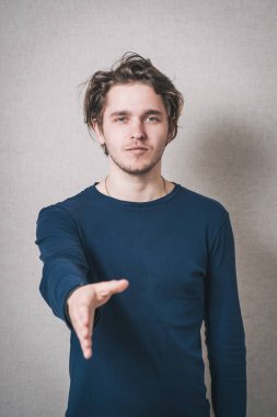 Adam merhaba demek için elini ileri uzattı. Gri arkaplan