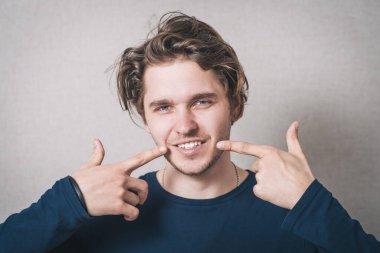 Gülümseyen ve sağlıklı dişleri olan bir adam. Gri arkaplan