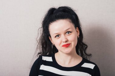 Uzun saçlı bir kadın kameraya bakıyor. Gri arkaplan