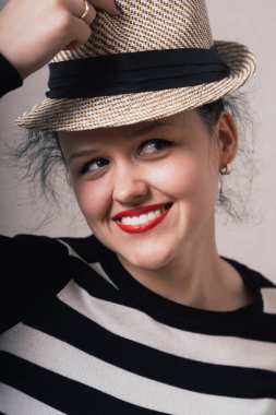 Kadın şapkasını ve kıyafetlerini çıkarıyor. Gri arkaplan.