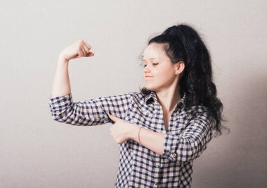 Kız stüdyo arka planında pazılarını gösteriyor.