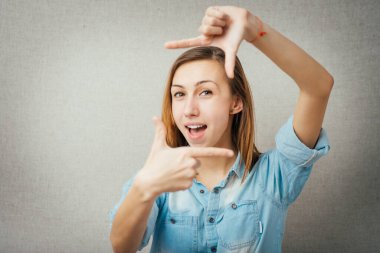 Kadın elinden bir çerçeve yapıyor. Gri arkaplanda izole