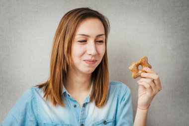 Kurabiye yiyen jest kadını. Gri arkaplanda izole