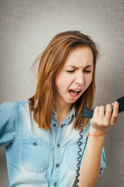 Telefonda konuşan bir kadın, telefona bağıran kızgın bir kadın. Gri arkaplanda izole