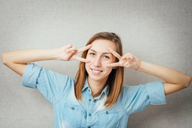Gri arka planda zafer gözlüğü takan genç bir kadın.